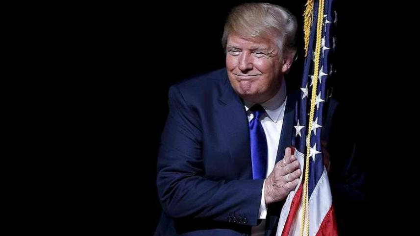 Donald Trump hugging a US flag.jpg