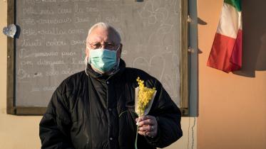 A man wearing a protective mask holds a bouquet of flowers